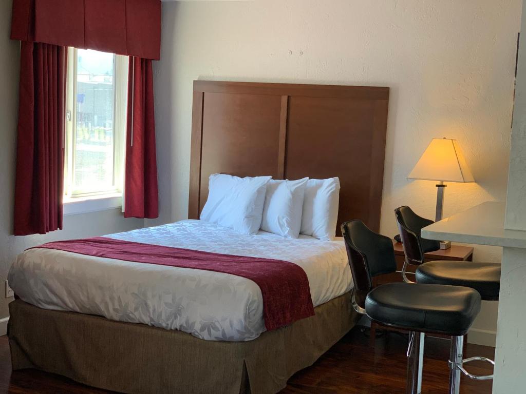 a hotel room with a bed and a table and chairs at Red Carpet Inn Medford in Medford