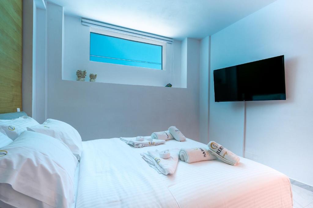 a bedroom with a bed with white sheets and a flat screen tv at Sardines Luxury Villas in Analipsi