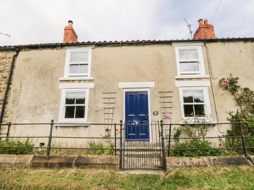 a house with a blue door and two windows at Primrose Hill Farmhouse in Hutton le Hole