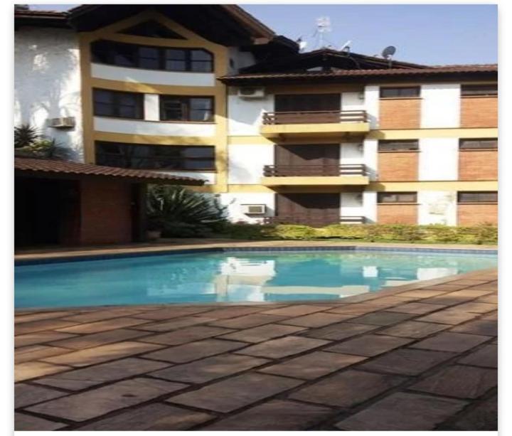 a swimming pool in front of a building at Apartamento no Residencial Swiss Jd Europa in Santa Cruz do Sul