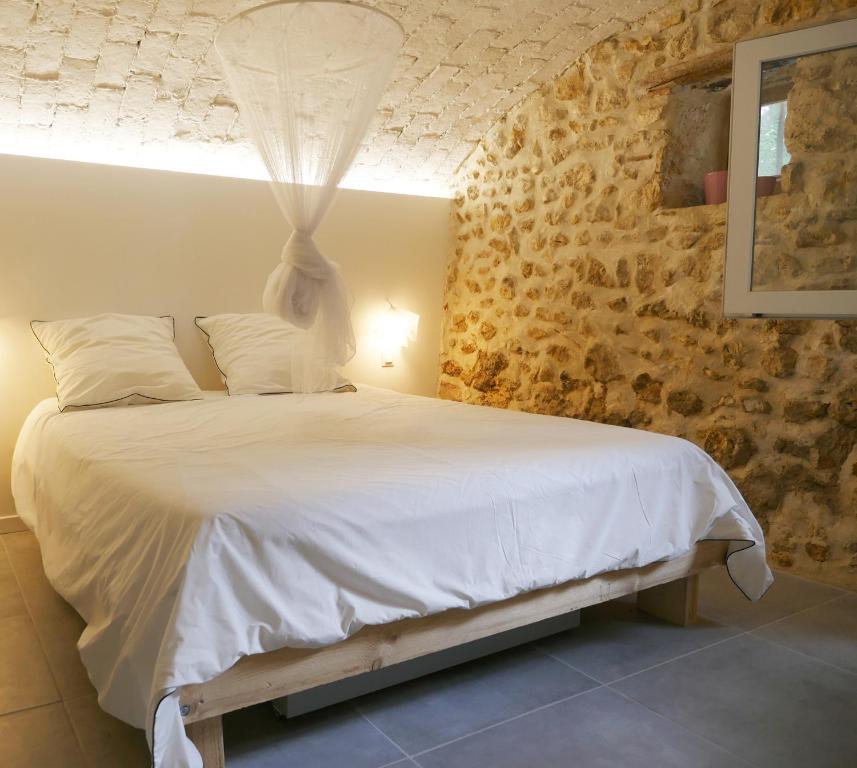 1 dormitorio con 1 cama con edredón blanco en L'Appartement de Séraphin, en Navacelles