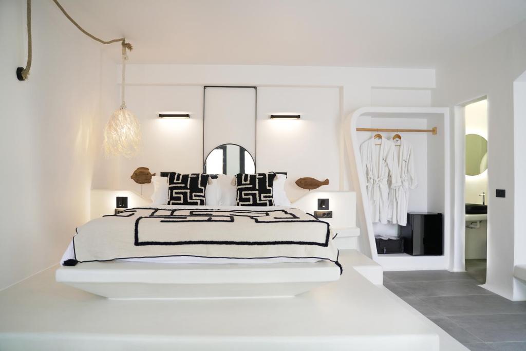 een witte slaapkamer met een bed en een spiegel bij King's Suites in Kamari