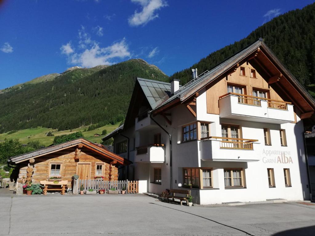 a large building with a mountain in the background at Apart Alba in Ischgl