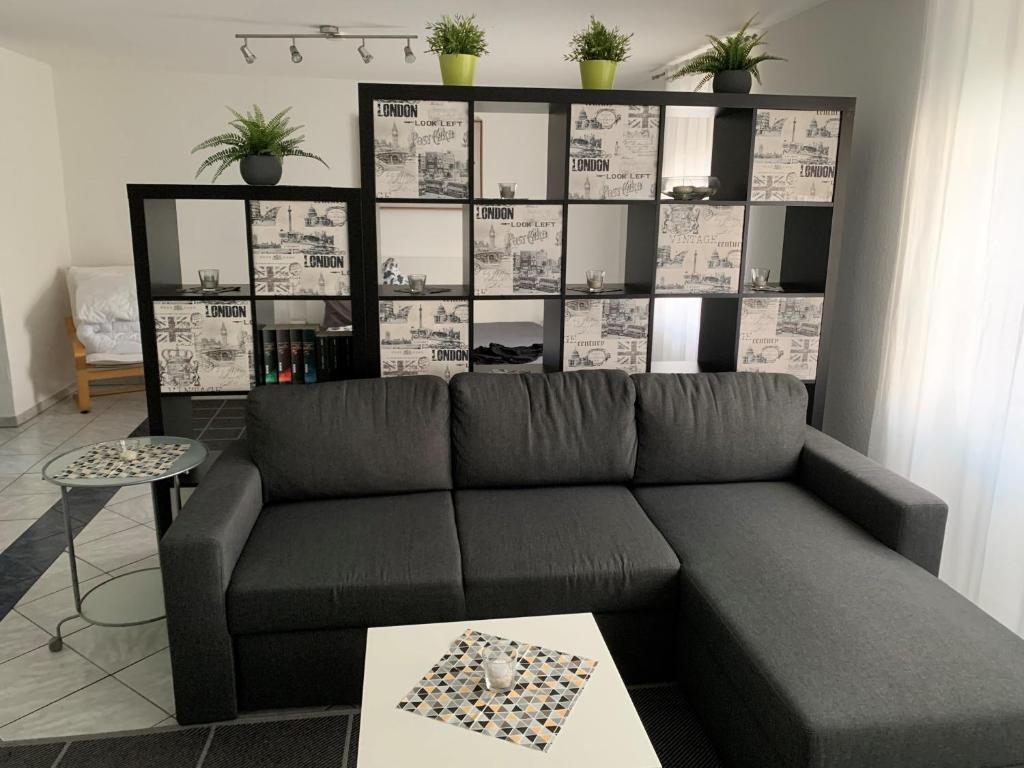 ein Wohnzimmer mit einem Sofa und einem Regal mit Topfpflanzen in der Unterkunft Ferienwohnung „ Zum Josefstal „ in Sankt Ingbert