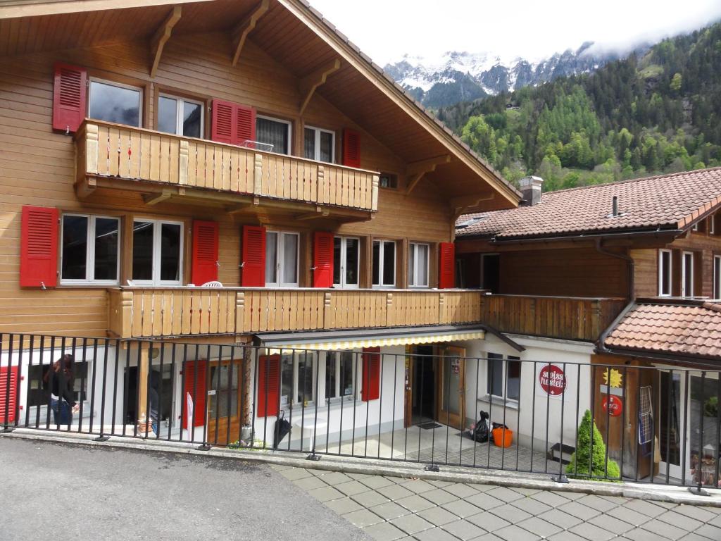 een groot houten gebouw met rode deuren en ramen bij Valley Hostel in Lauterbrunnen