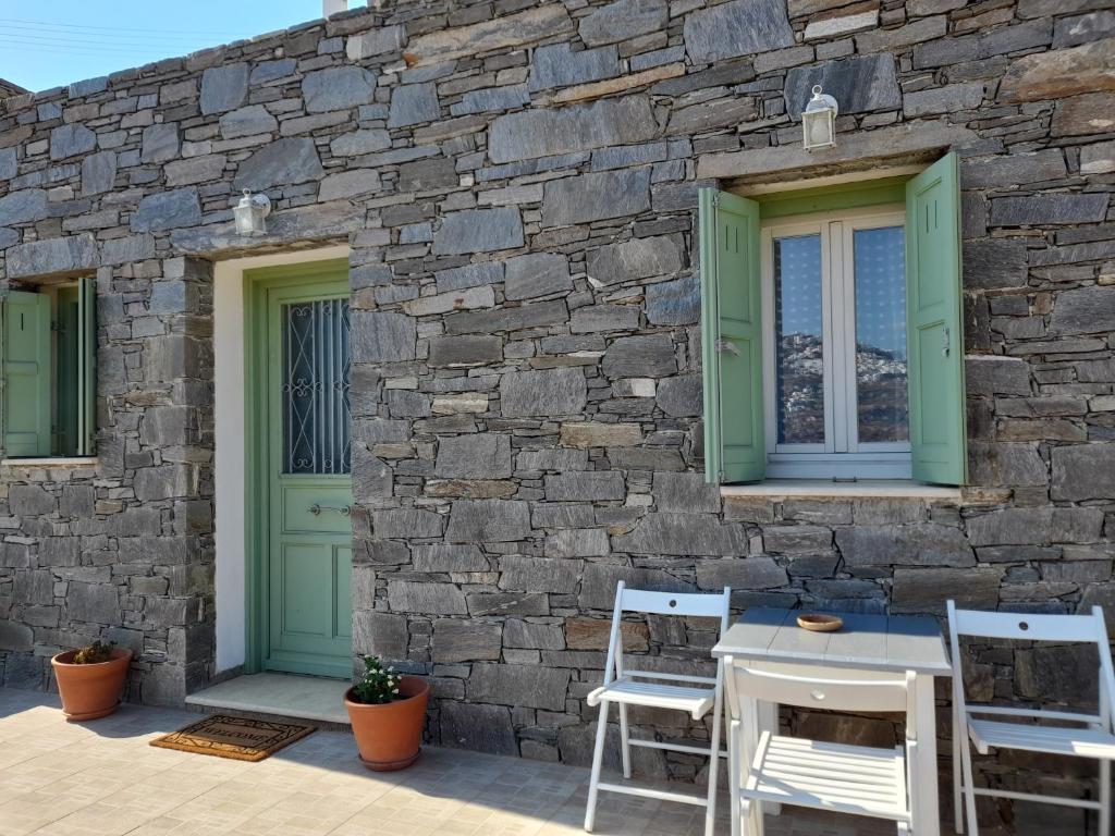 a stone wall with green doors and chairs on a patio at Magda house in Livadi