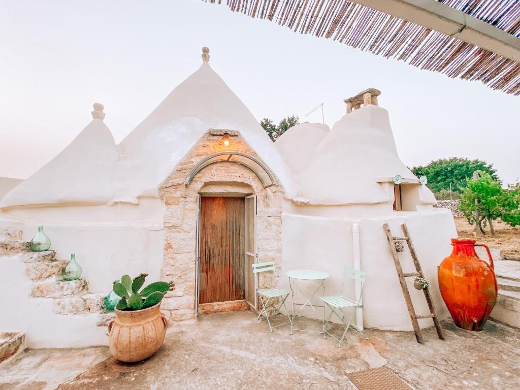 Casa blanca con puerta, mesa y sillas en Trullo Bianco Ostuni, en Ostuni