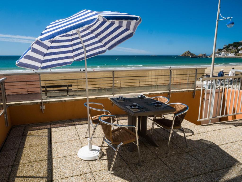 - une table et des chaises avec un parasol sur la plage dans l'établissement La Digue, à Pléneuf-Val-André