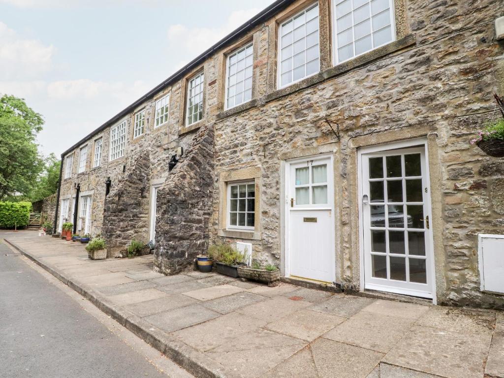 un edificio de piedra con puertas y ventanas blancas en 9 Riverside Walk, en Skipton