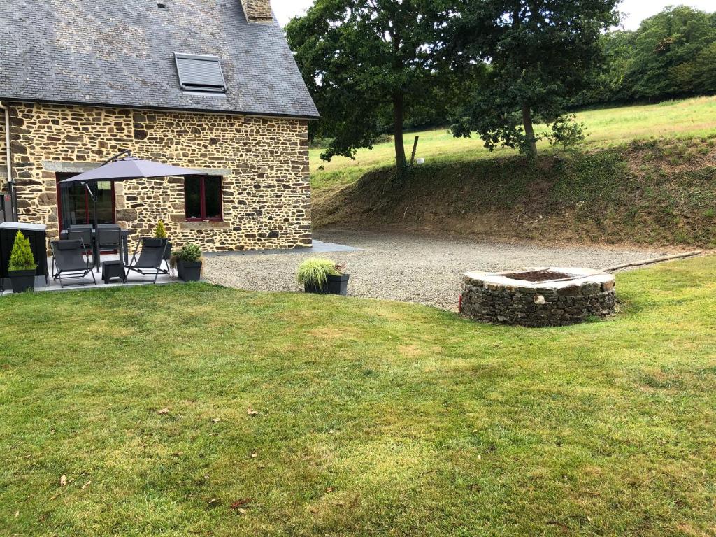 uma casa de pedra com uma mesa e cadeiras num quintal em A 20 kms du Mont St Michel, Charme à la campagne em Saint-Senier-de-Beuvron
