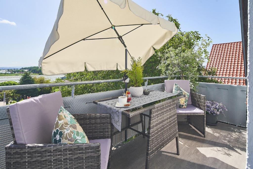 einen Tisch und Stühle mit Sonnenschirm auf einer Terrasse in der Unterkunft Ferienwohnung Bodensee in Raderach in Friedrichshafen