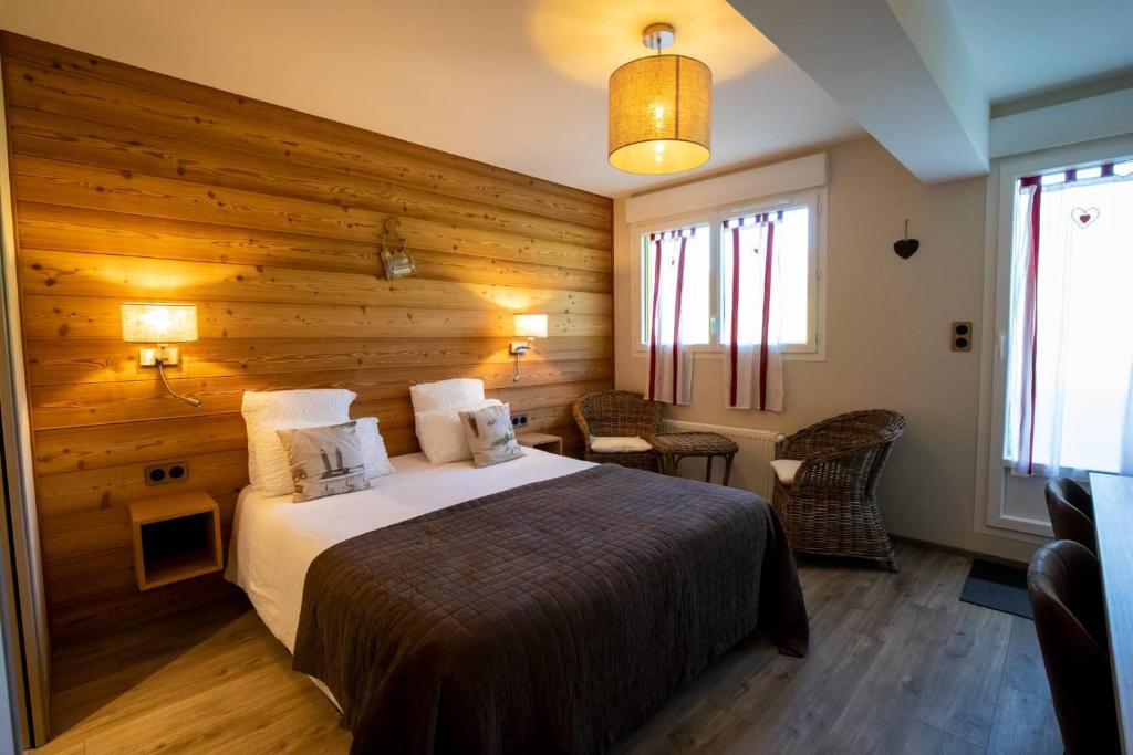 a bedroom with a bed and a wooden wall at Logis Le Vernay in Autrans