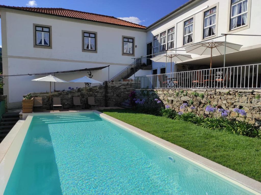 a swimming pool in front of a house at Quinta da Travessa - Douro in Covelinhas