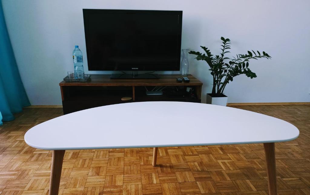 una mesa blanca en la sala de estar con TV en Mieszkanie Turkus w Gnieźnie en Gniezno