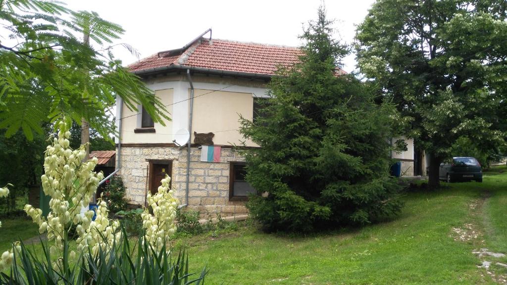 a small house in a yard with trees and flowers at Къща под наем PETROVA in Cherven