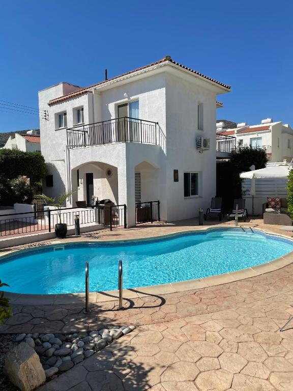 a villa with a swimming pool in front of a house at Villa Laurel in Peyia