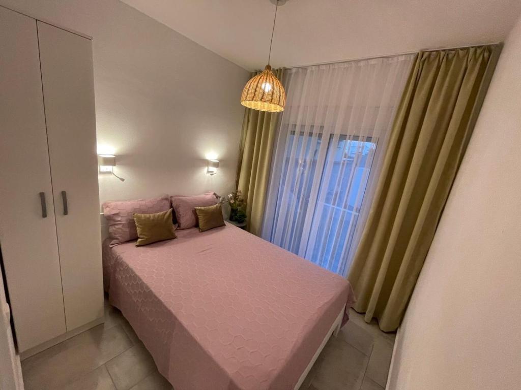 Un pequeño dormitorio con una cama rosa y una ventana en Villa Hanna, en Ulcinj