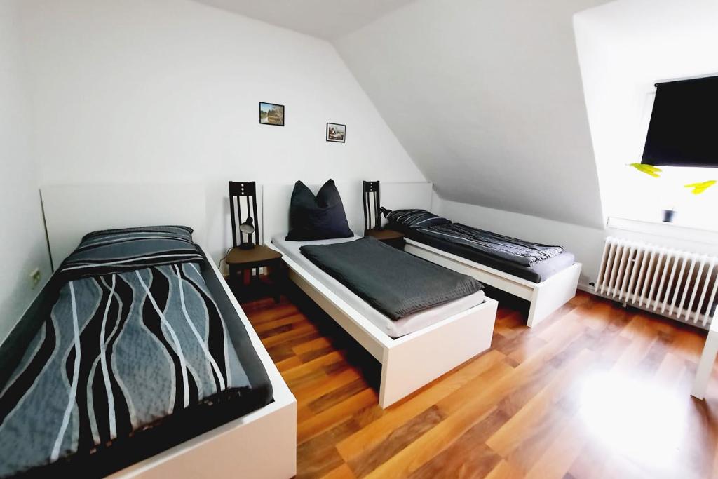 two beds in a room with wooden floors at Work & Stay Apartment mit TV & WLAN in Kleve