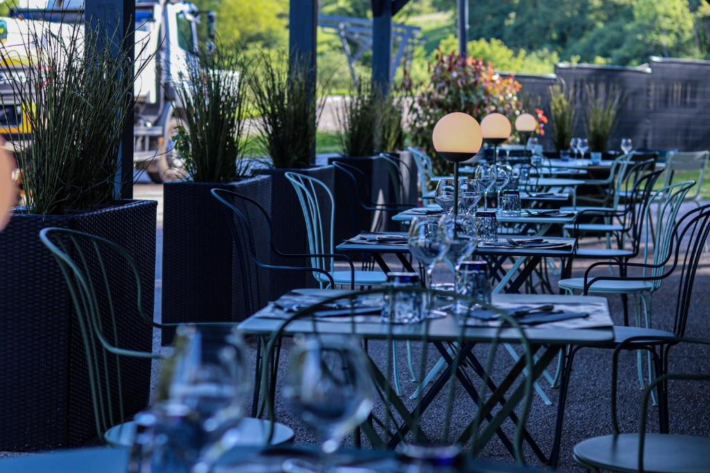 uma fila de mesas e cadeiras com copos de vinho em Hôtel Logis Restaurant La Fontaine em Mantry