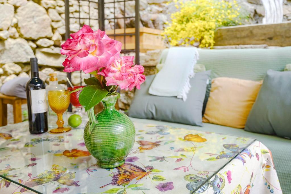 un jarrón verde con flores rosas sobre una mesa en El Naturalista - Los sitios de aravalle, en Casas del Abad