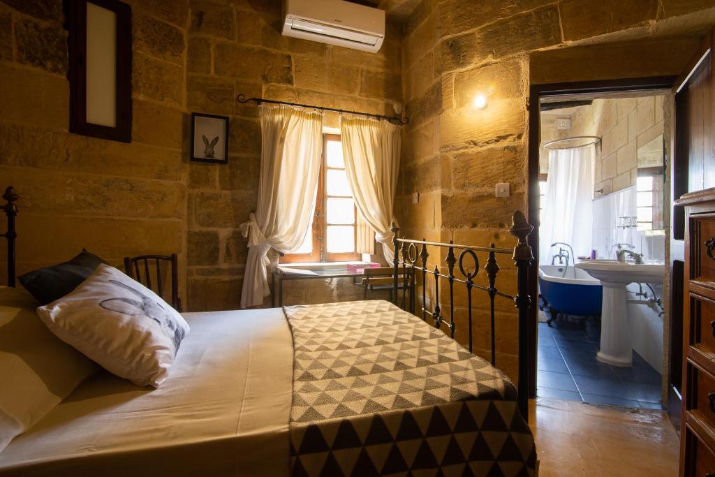 1 dormitorio con 1 cama y baño con lavamanos en The Burrow Guest House, en Tarxien