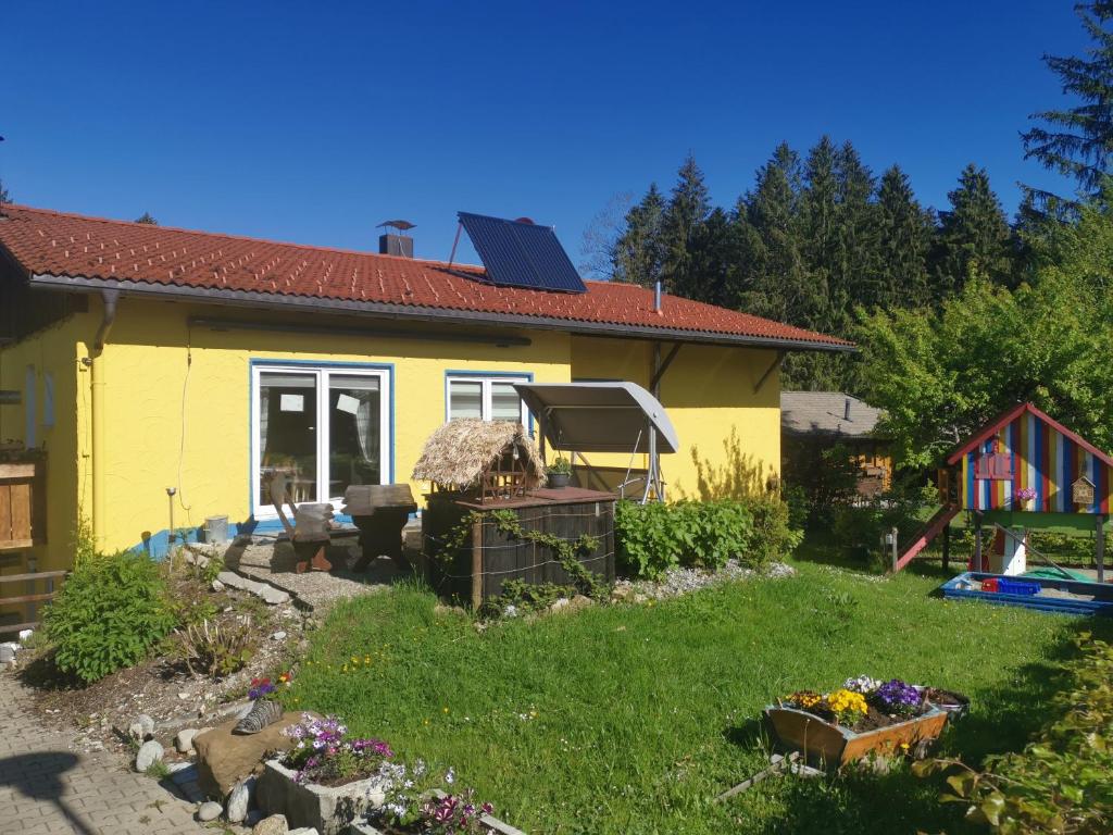 une maison jaune avec un jardin en face dans l'établissement Ferienwohnung im Landhausstil, à Oberreute