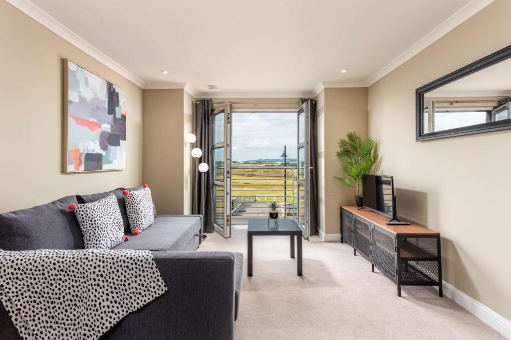 a living room with a gray couch and a television at Old Prestwick View - Donnini Apartments in Prestwick