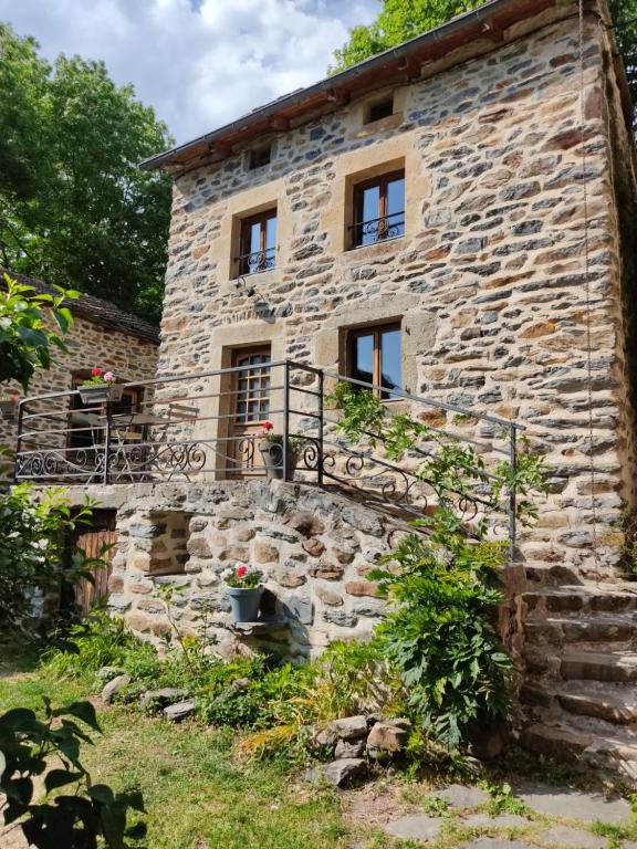 uma antiga casa de pedra com janelas e uma varanda em Gîte Le p'tit nid de Riouffreyt em Le Pertuis