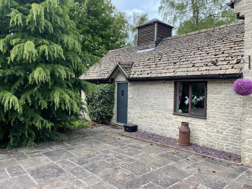 una casa in mattoni con una porta blu e un albero di Nethercote Cottage, Kingsize bed, Seven Springs Cottages a Cheltenham