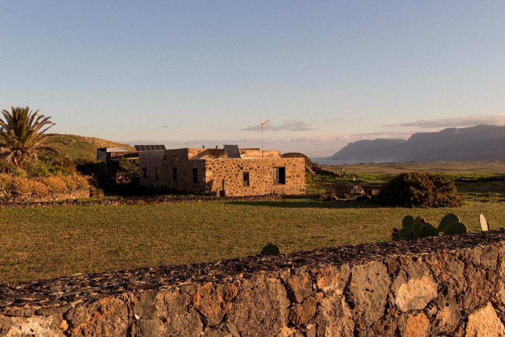 an old building in a field with a stone wall at Joya del Jable in Tao