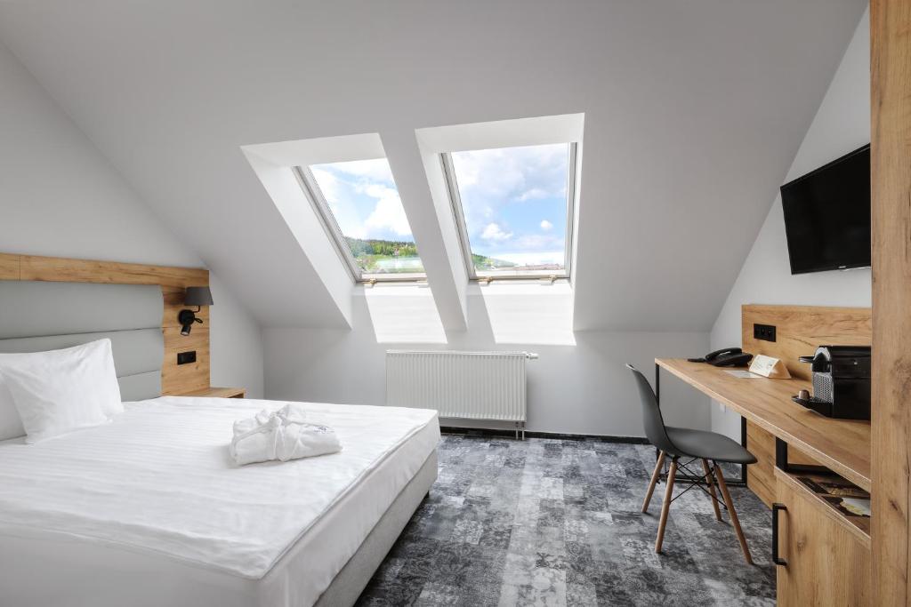 a bedroom with a bed and a desk and two windows at Hotel Vivaldi in Karpacz