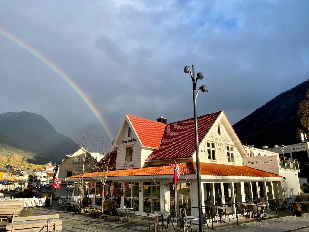 a rainbow in the sky over a town with a building at Stryn Kaffebar & Vertshus in Stryn