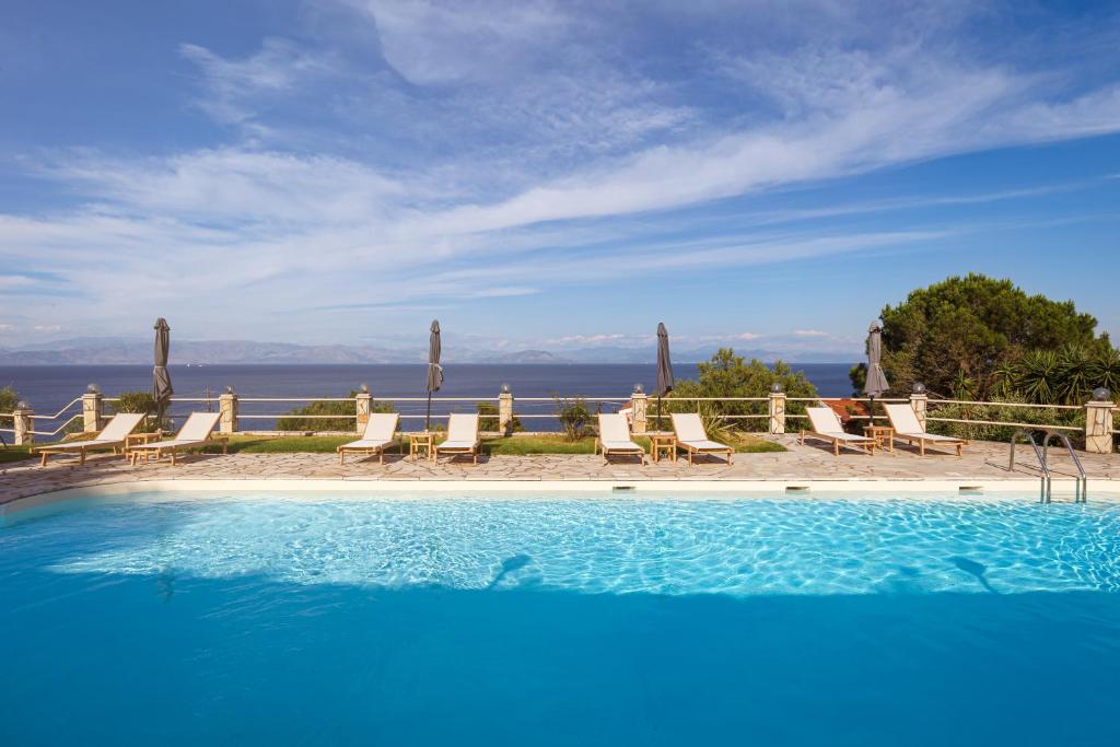 a swimming pool with chairs and a view of the ocean at Anasa Corfu in Benitses