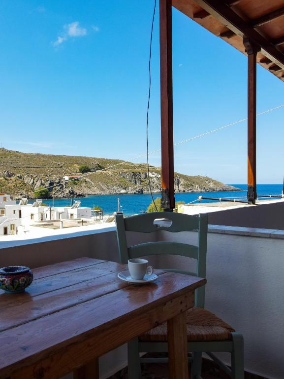 a wooden table with a cup of coffee sitting on a balcony at Mistral-Patmos in Patmos