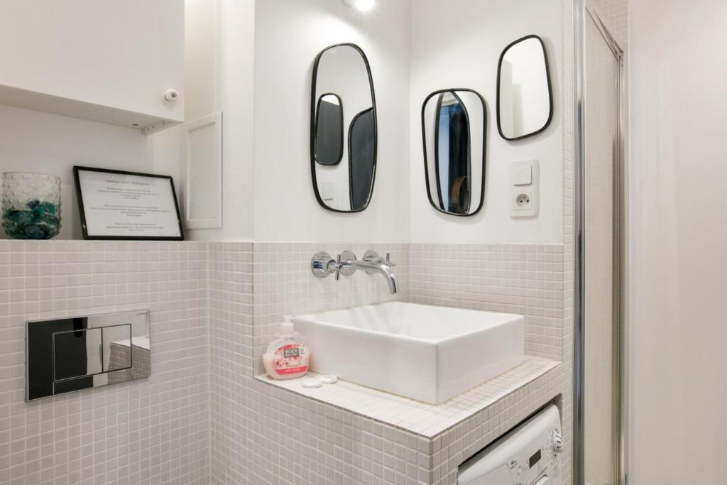 a bathroom with a sink and mirrors on the wall at Cozy studio 10 min from Eiffel Tower Invalides Beaugrenelle in Paris