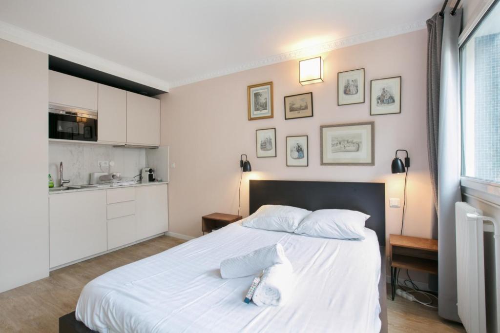 a bedroom with a large white bed and a kitchen at Cozy studio 10 min from Eiffel Tower Invalides Beaugrenelle in Paris