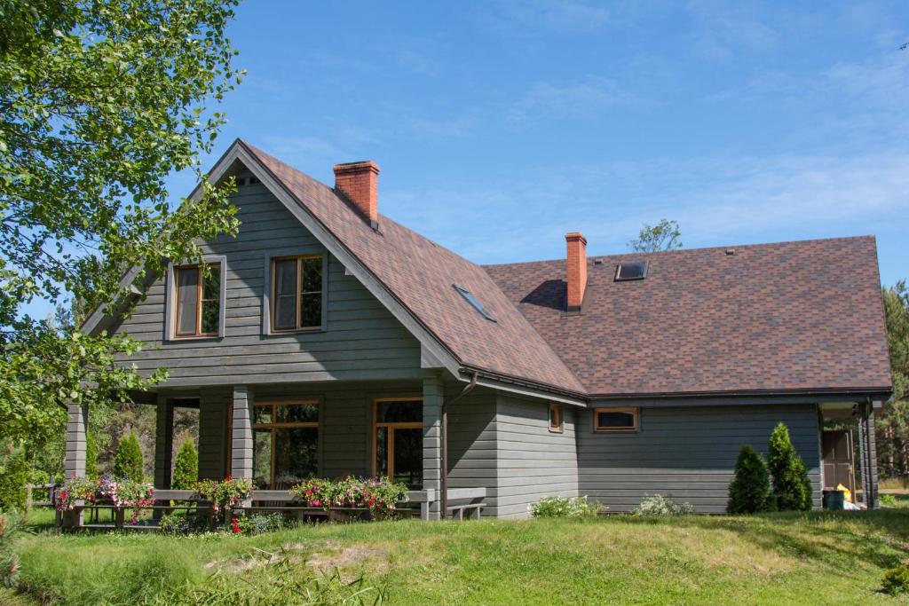 a gray house with a brown roof at Guest House Pītagi in Košrags