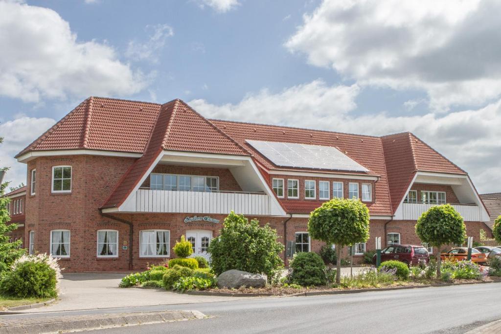 a large brick building with a red roof at Landhaus Oltmanns in Moormerland