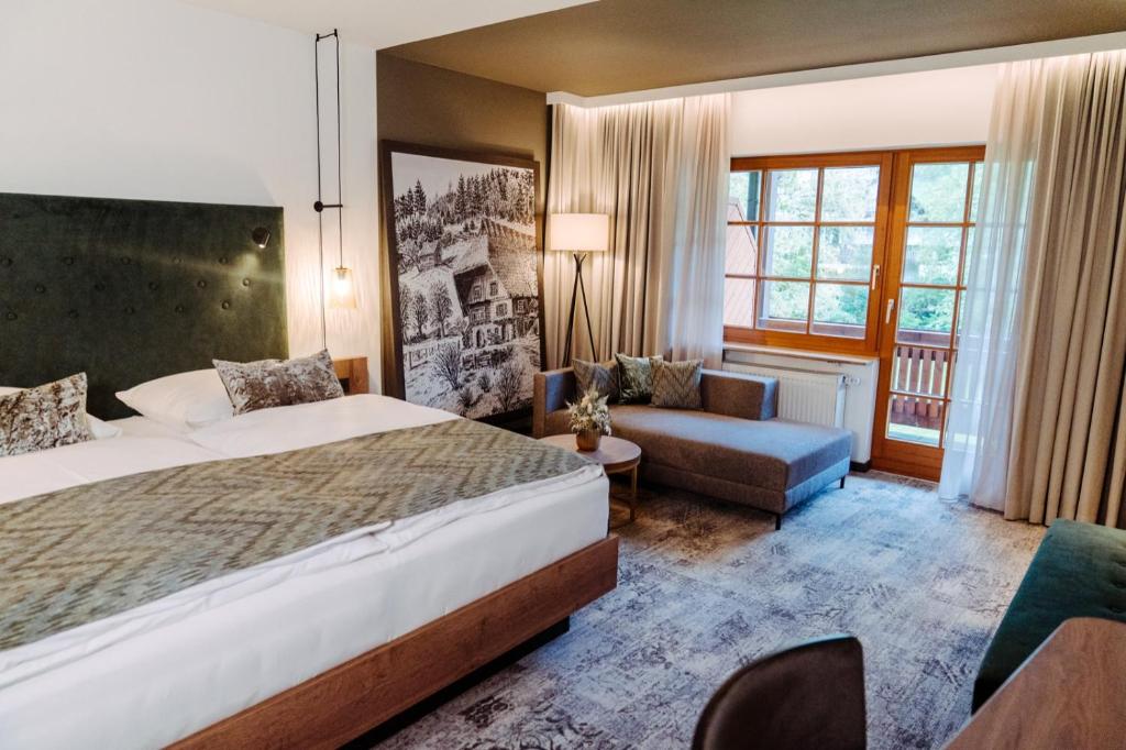 Cette chambre comprend un grand lit et un canapé. dans l'établissement Landhotel Hirschen, à Oberwolfach