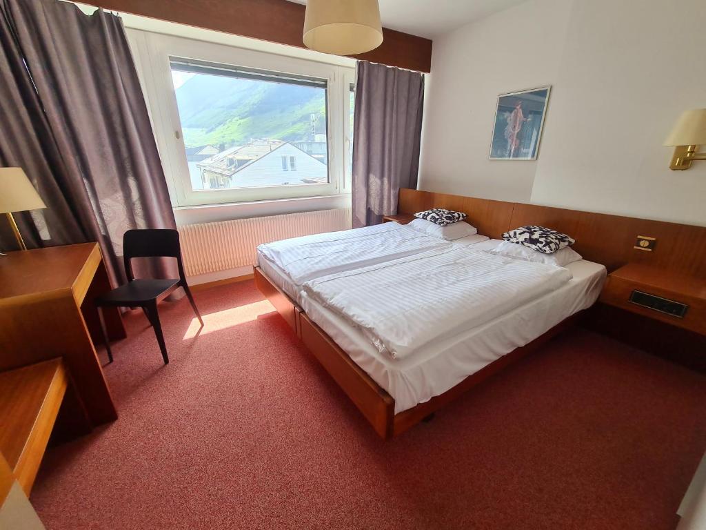 a hotel room with a bed and a window at Hôtel de la Poste Martigny - City Center in Martigny-Ville