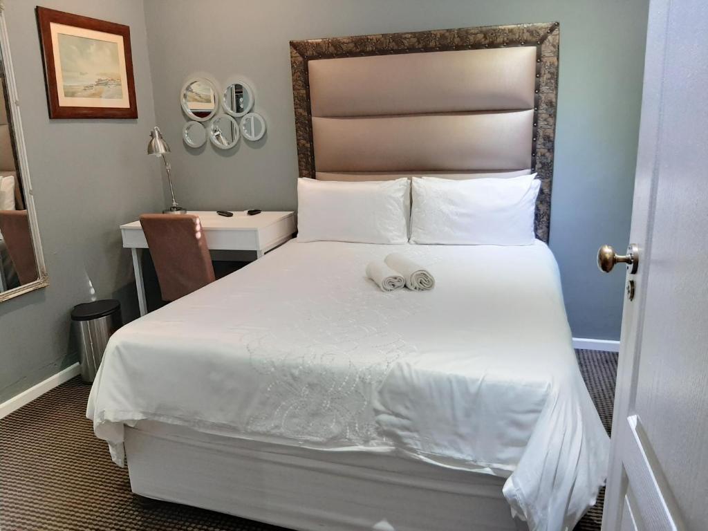 a bedroom with a large white bed with a desk at VIRGINIA TOWNHOUSE in East London