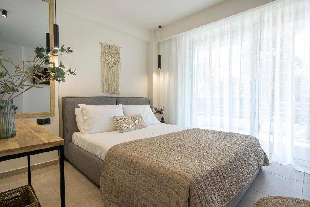 a bedroom with a bed and a large window at Aelia Seaside Luxury Suites in Néa Karváli