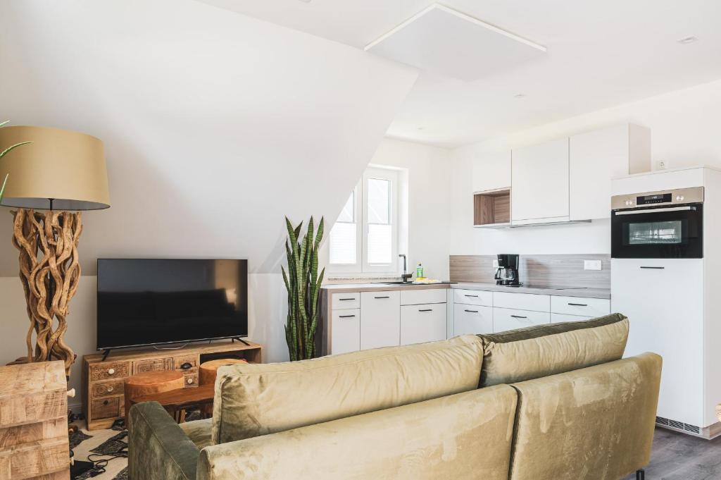 ein Wohnzimmer mit einem Sofa und einer Küche in der Unterkunft Dünenquartier Apartment 22 in Zingst