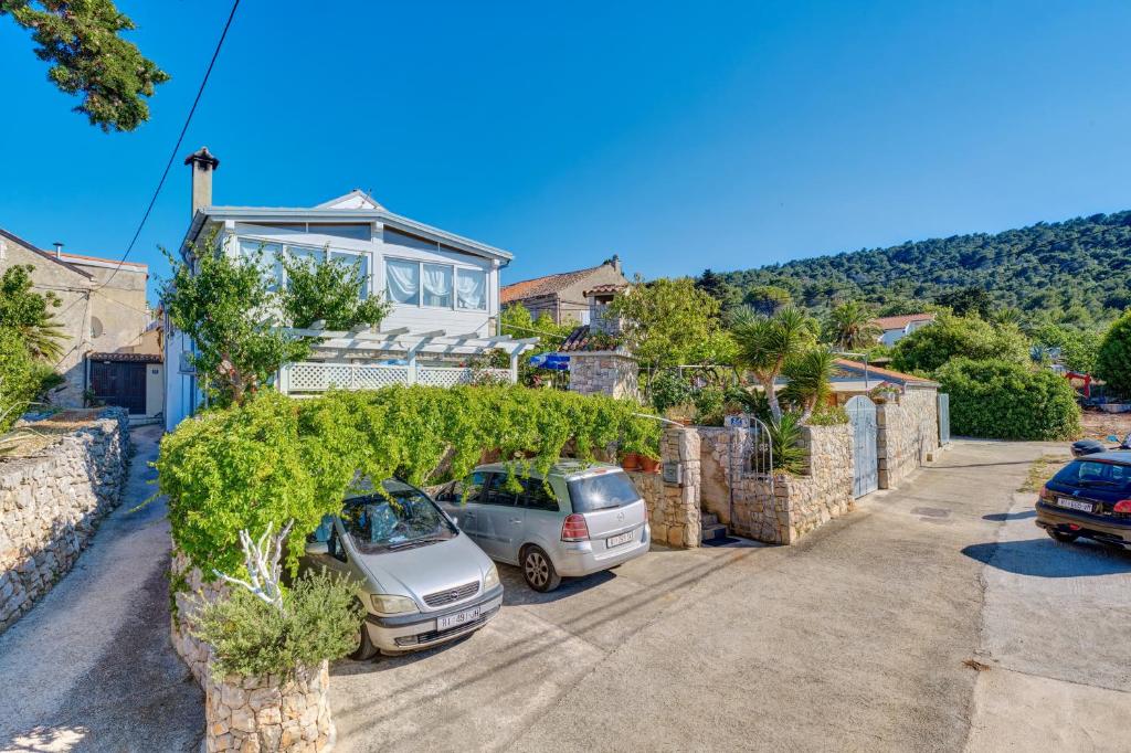 a house with two cars parked in a driveway at Apartment Neno in Veli Lošinj