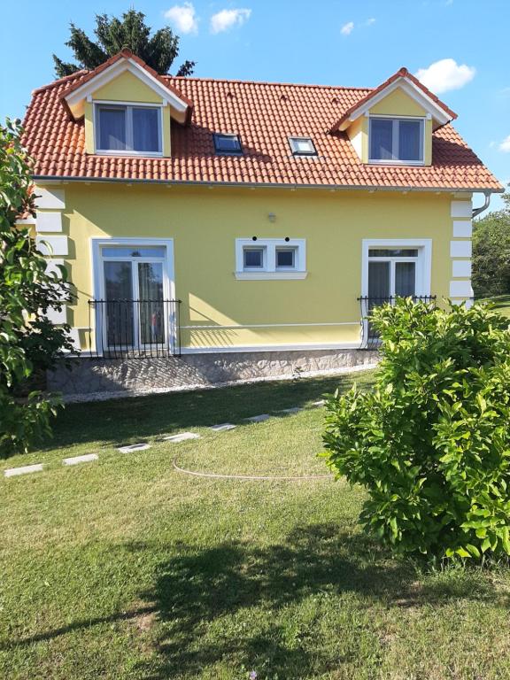 una casa amarilla con techo rojo en Kondics Apartmanház, en Sárvár