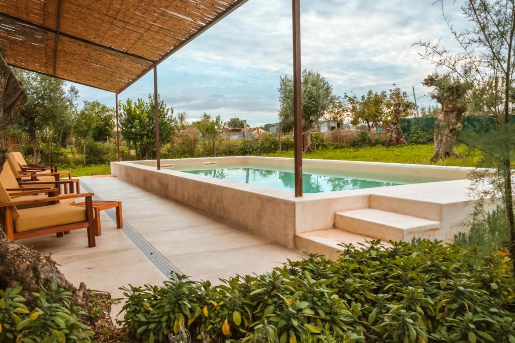 - une piscine dans un jardin avec des chaises et une table dans l'établissement São Brás do Regedouro - Turismo na Aldeia, à Évora