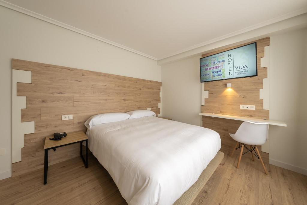 um quarto com uma grande cama branca e uma secretária em Hotel VIDA Finisterre Centro em Finisterre