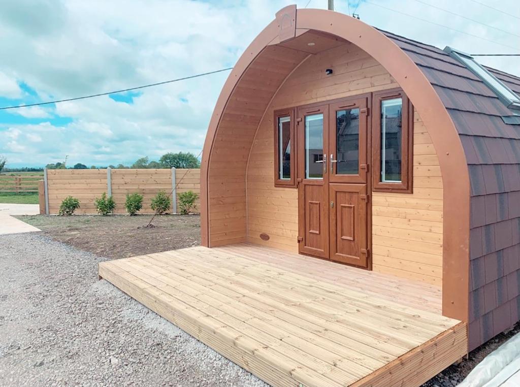 a building with a wooden door and a wooden deck at Glastonbury Glamping in Wells