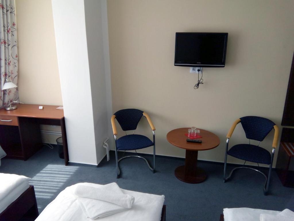 a room with two chairs and a table and a tv at Arkada Hotel in Bučovice