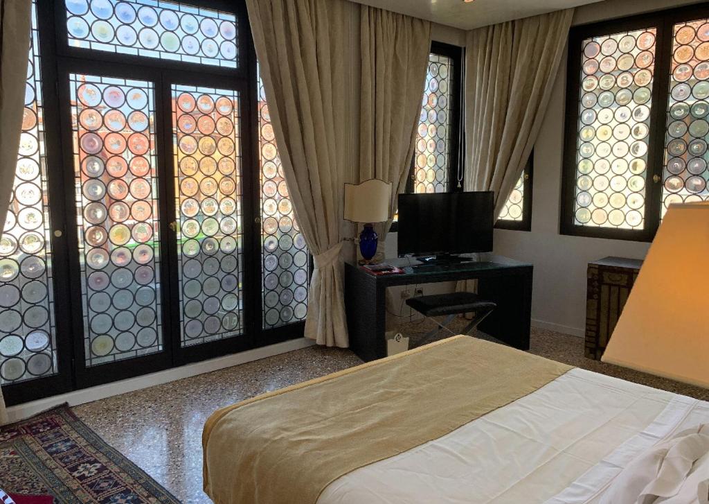 a bedroom with a bed and a tv and windows at Ca' Nigra Lagoon Resort Adults Only in Venice